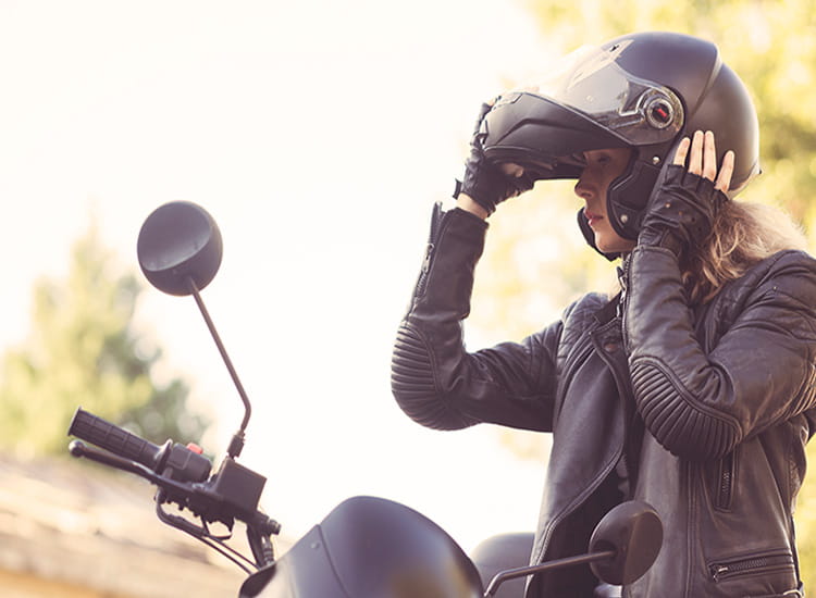 female rider securing helmet beside her bike